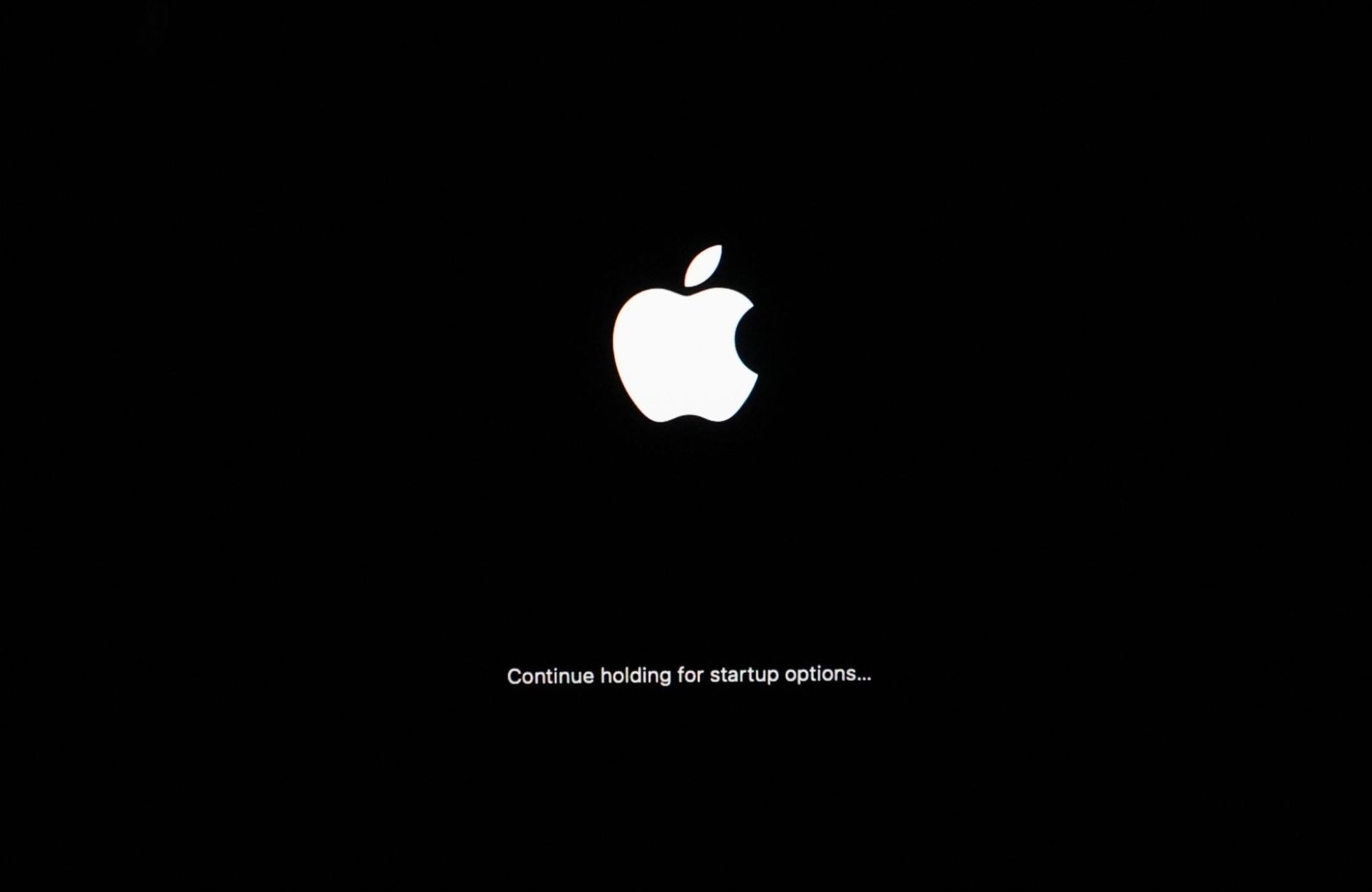 Apple laptop power button circled and held down to load the startup options screen and enter Recovery Mode on an Apple Silicon Mac.