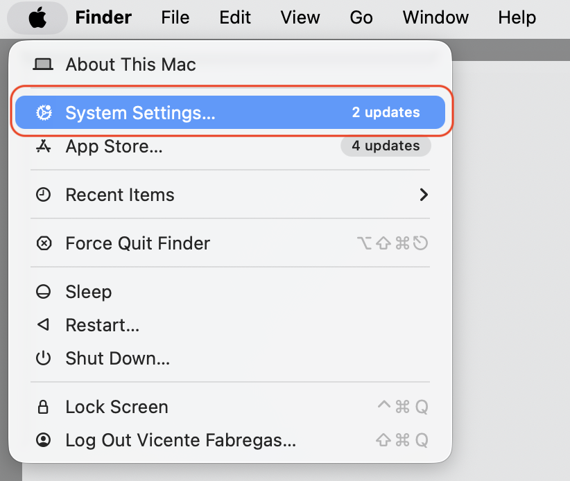 The Apple menu open on macOS Tahoe with System Settings highlighted to begin assigning Spotlight to a Hot Corner on a MacBook.