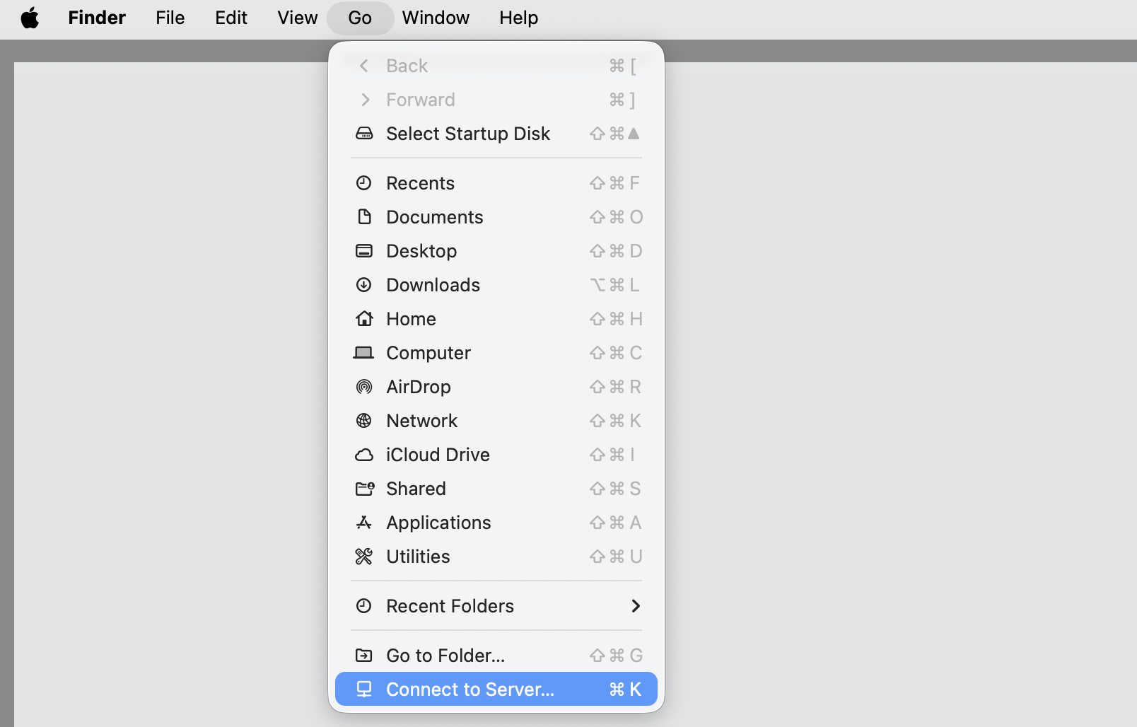The Finder Go menu open on a MacBook, where you choose Connect to Server to reach a shared Mac that is not listed under Locations.