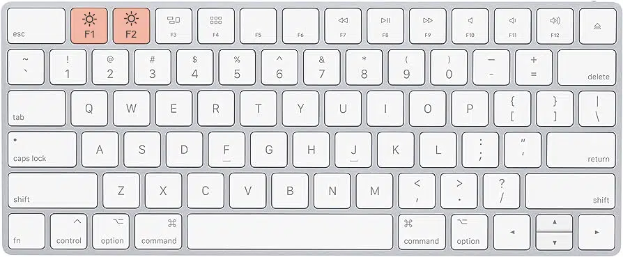 A mockup of a Mac keyboard is displayed. Charge a MacBook properly by reducing the brightness using the keyboard keys F1 and F2.