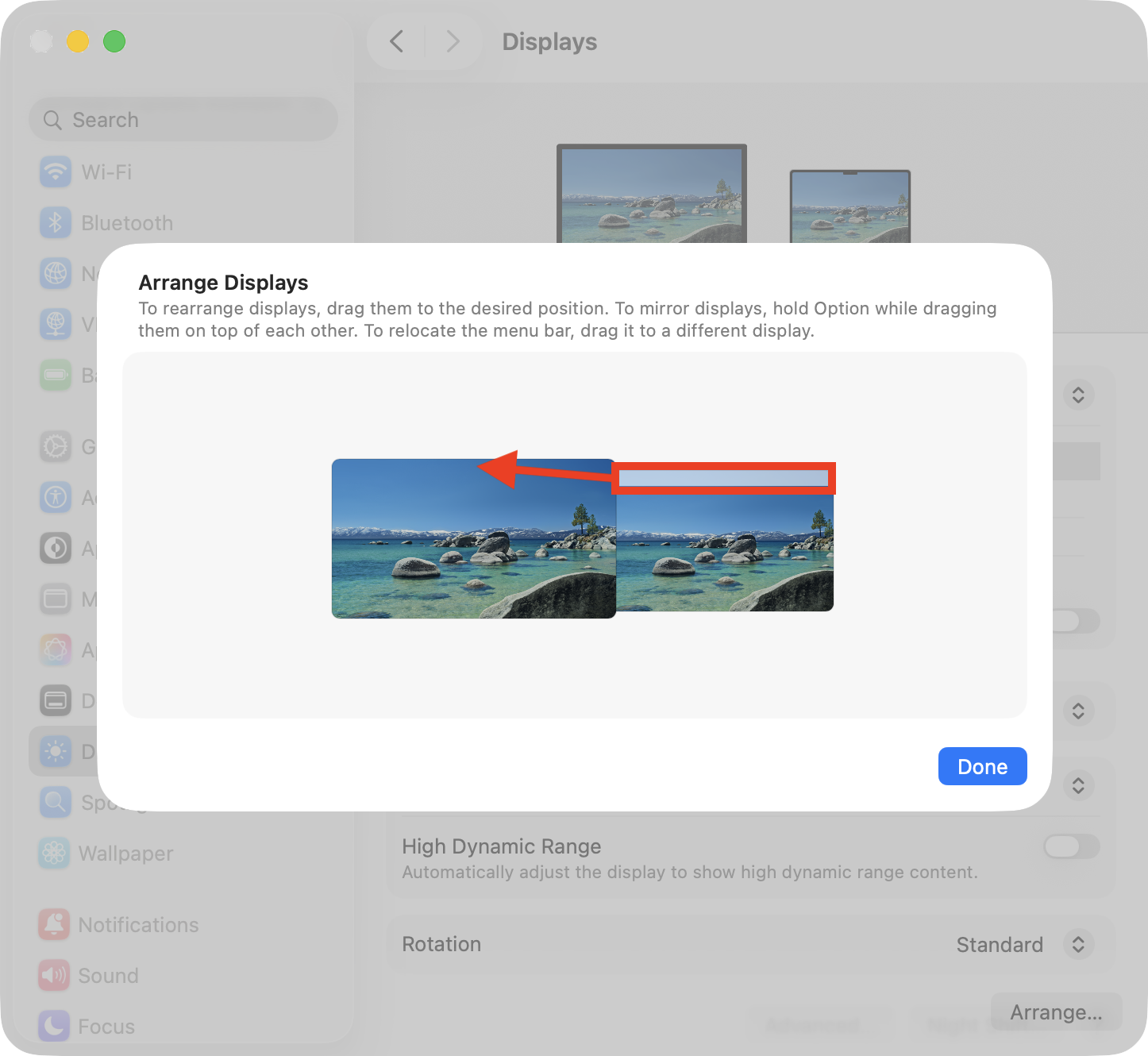 The Arrange option inside System Settings > Displays on Mac. Move the Mac menu bar to your primary display to fix the Mac Dock in place so that it doesn't show on all screens as you move between them.