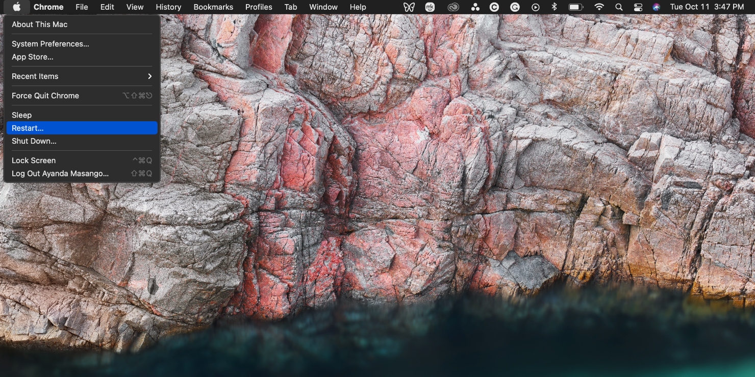 The restart option is highlighted on Apple's drop-down menu from the menu bar against a natural desktop image on a MacBook Pro device