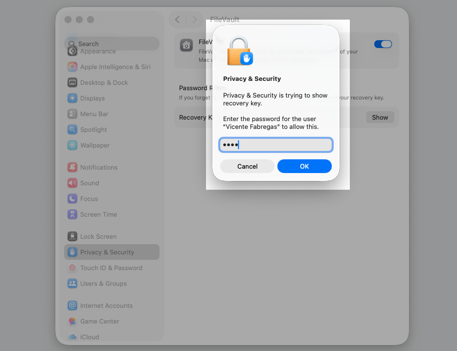 The macOS Privacy & Security prompt on a MacBook asking for the user password and OK button to unlock and show the FileVault Recovery Key.